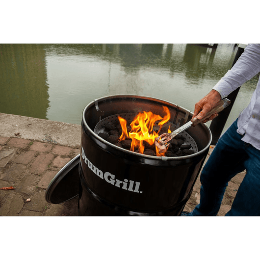 Iemand die een olievat vuurkorf annex barbecue op een kade aan het aanmaken is.