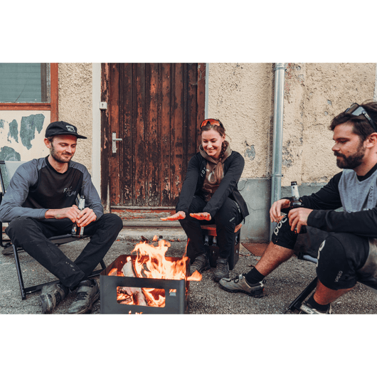 Corten stalen Beer Box vuurschaal van Höfats met brandend vuur met 3 mensen die genieten van de warmte.
