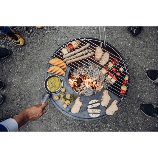 Höfats Bowl vuurschaal. Van bovenaf gefotografeerd met diverse etenswaren op de plancha en rvs rooster.