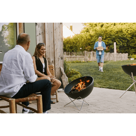 Man en vrouw op ee terras met de Höfats vuurkorf brandend naar zich toe. 