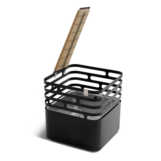 Zwarte Höfats Cube vuurkorf van gepoedercoat roestvrij staal, stijlvolle en multifunctionele vuurkorf met grillrooster ten behoeve van een vis.