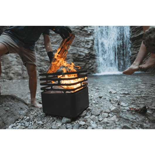 Man rookt een zalm op de houten grillplank met een Höfats Cube vuurkorf van zwart roestvrij staal.