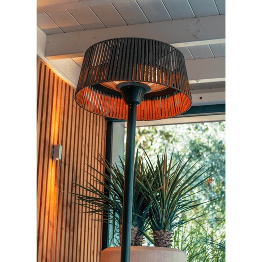 Zwarte staande heater met olifin kap onder houten veranda met glazen deur. 