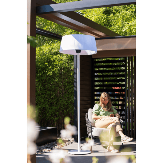 Witte staande heater bij een loungestoel onder houten veranda.