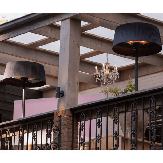Zwarte staande heater onder houten veranda bij tuintafel.